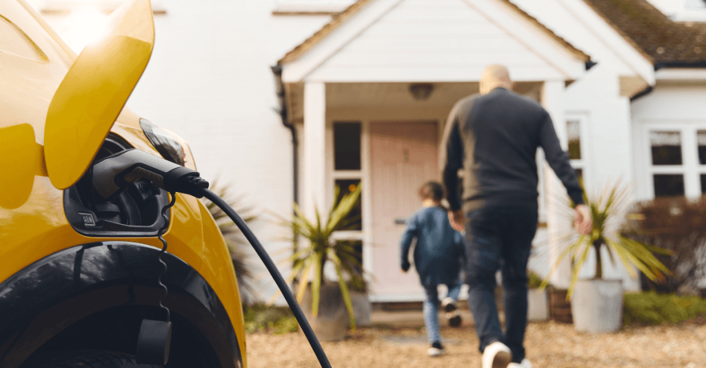 Electric vehicle charging while man and child walk toward house